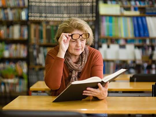 Woman having trouble reading in library